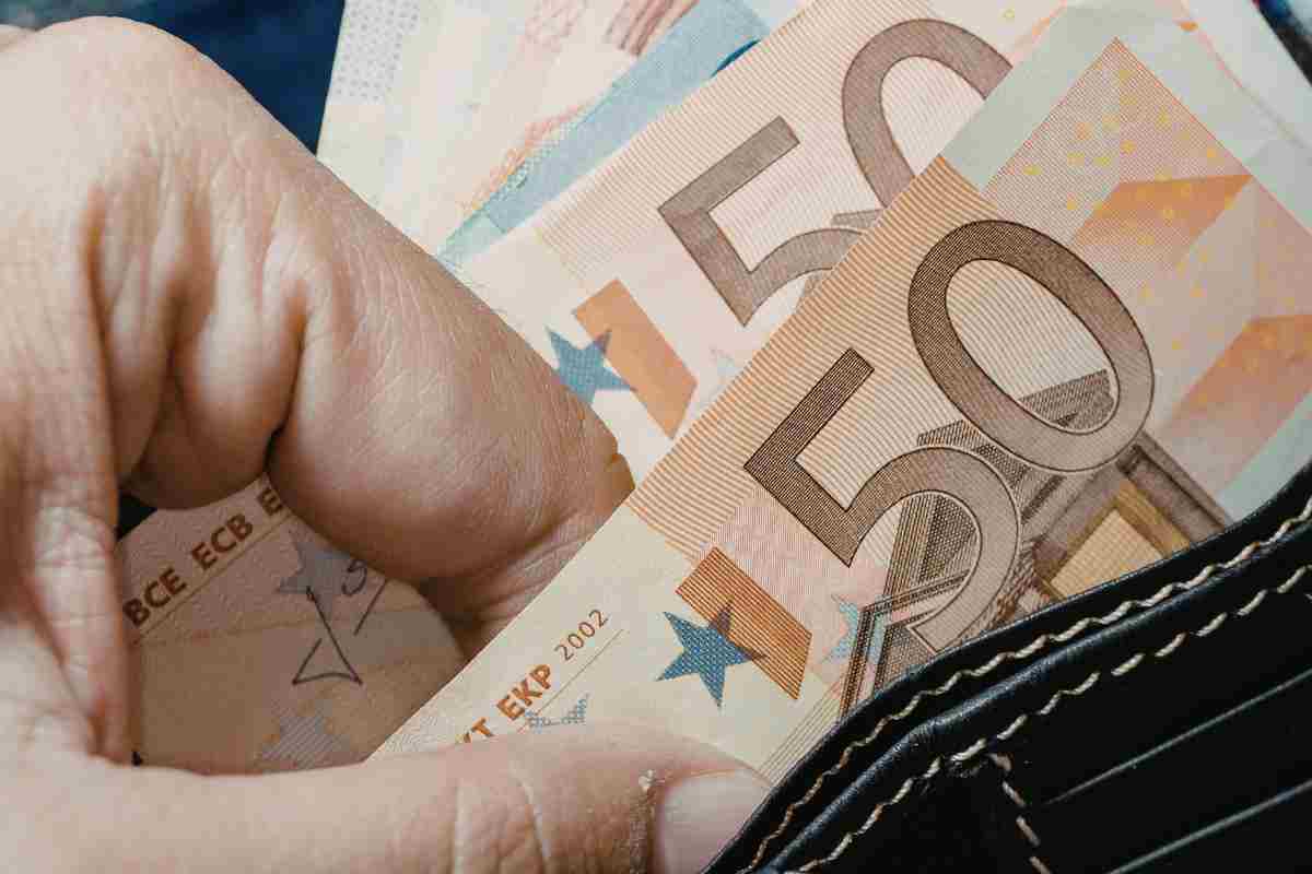 una mano prende 50 euro dal portafoglio
