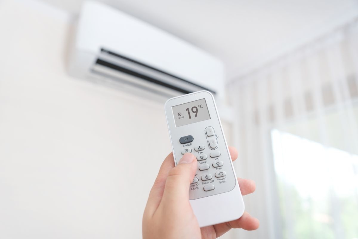 mano che accende condizionatore con telecomando