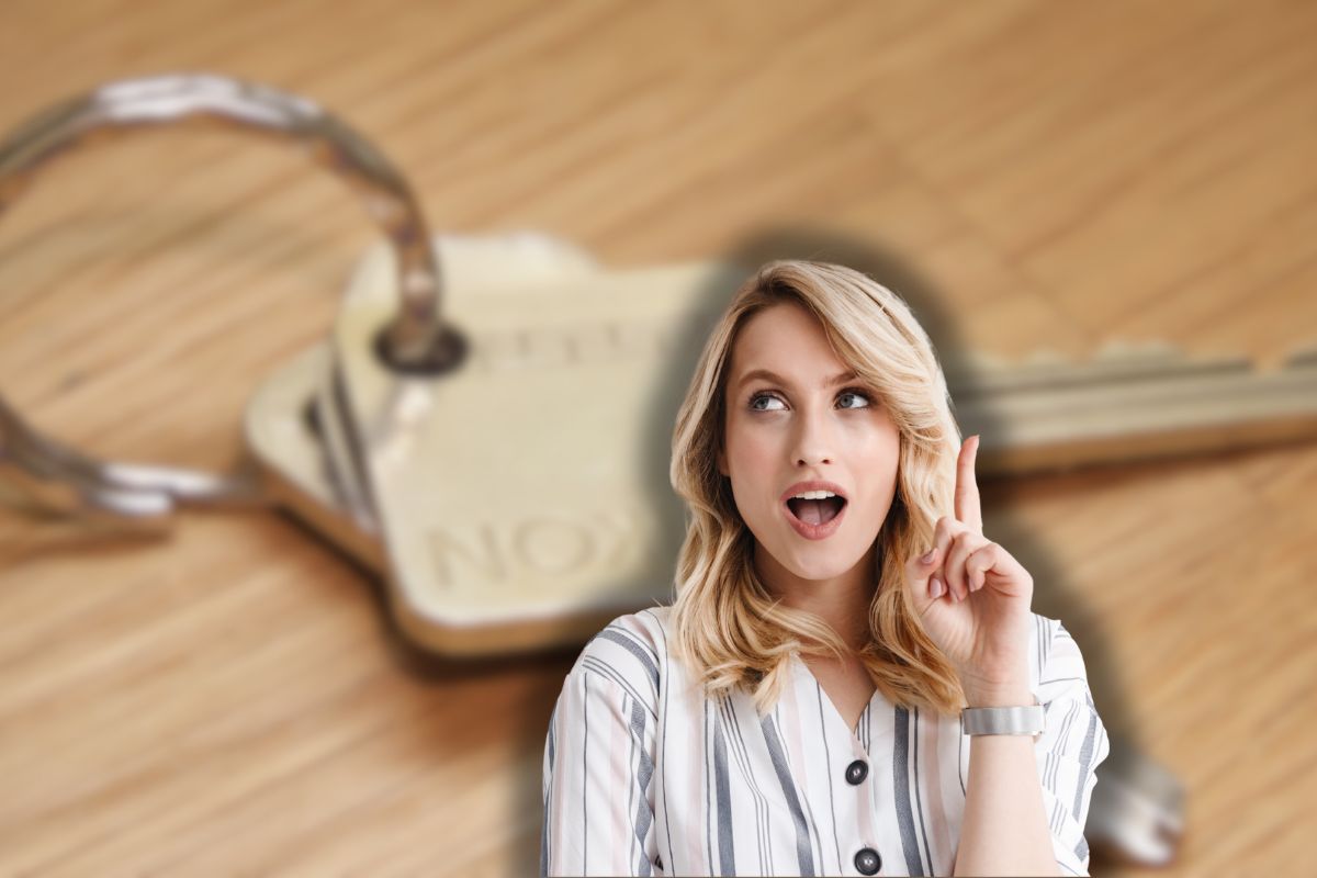 chiavi di casa su tavolo di legno e donna sorpresa che ha un'idea