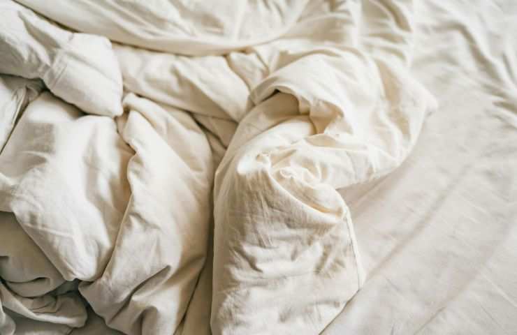 letto sfatto con lenzuola bianco