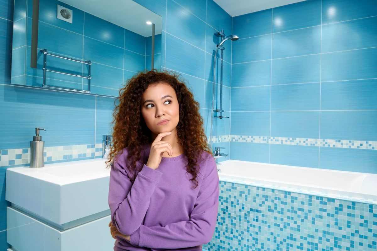 donna che pensa all'interno di un bagno con piastrelle azzurre