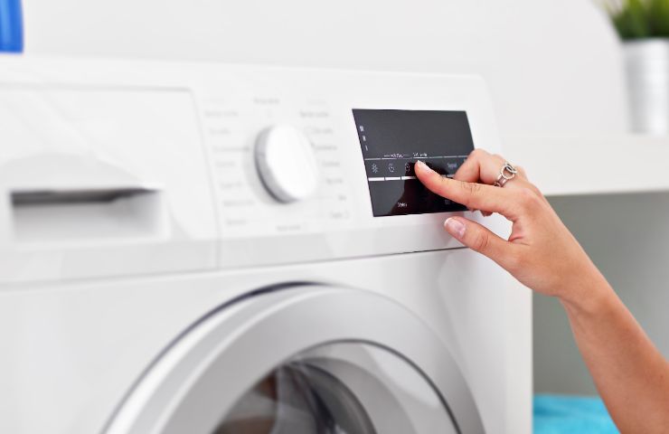 donna che preme pulsante lavatrice