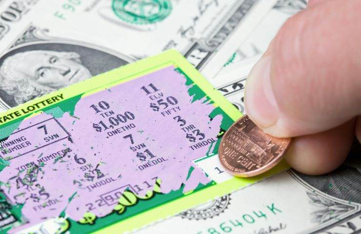 uomo che usa monete su un gratta e vinci