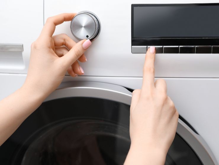 mani che impostano funzioni lavatrice