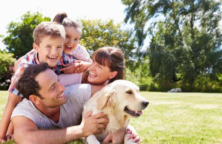 famiglia sorridente all'aria aperta insieme al loro cane