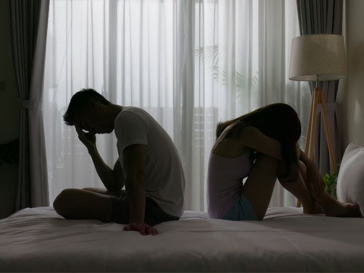 coppia in crisi che si volta le spalle sul letto